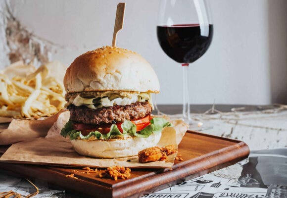 A burger with a glass of wine in the background